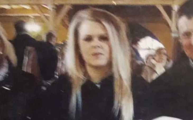 Młoda kobieta w czarnym ubraniu, siedząca w towarzystwie innych osób.