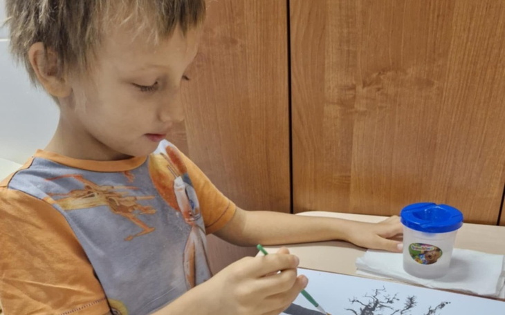 Chłopiec malujący obraz, skupiony na pracy.