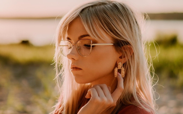 Młoda kobieta z okularami, dotykająca kolczyka w kształcie węża.