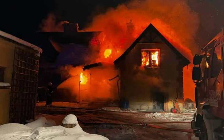 Płonący dom w nocy, z intensywnym ogniem i dymem.