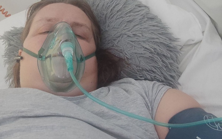 Kobieta w szpitalu, z maską tlenową na twarzy.