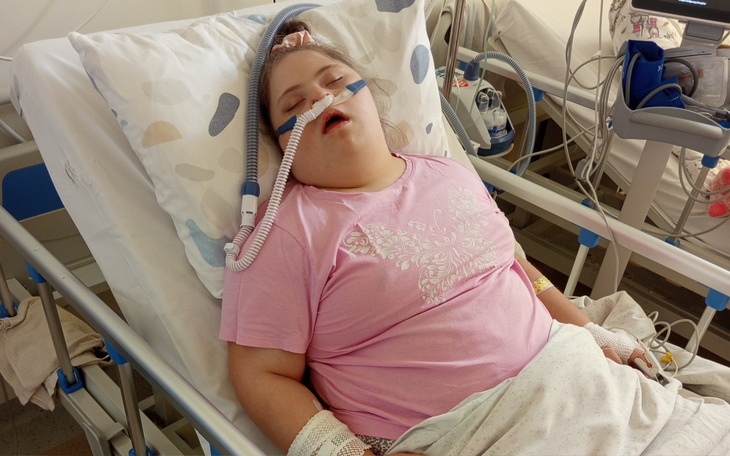 Dziewczynka w szpitalnym łóżku z respiratorem.