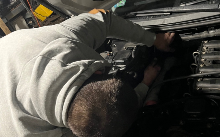 Mężczyzna naprawia silnik samochodu w warsztacie.