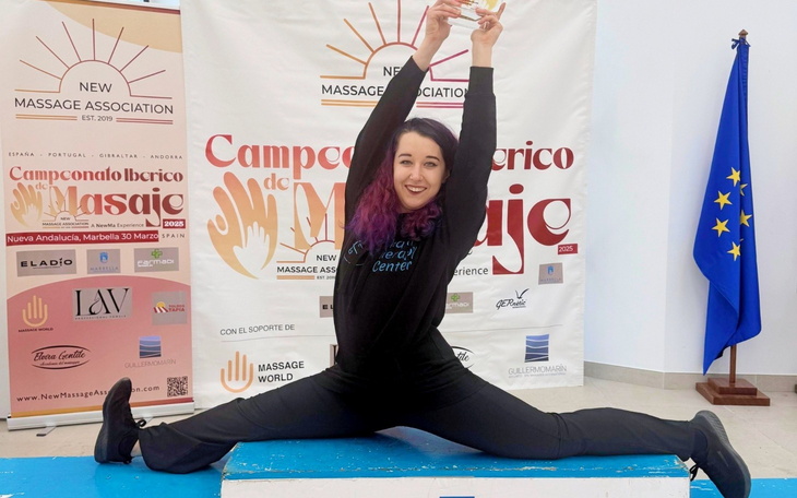 Zwycięzca konkursu masażu z nagrodą w ręku, w radosnej pozie.