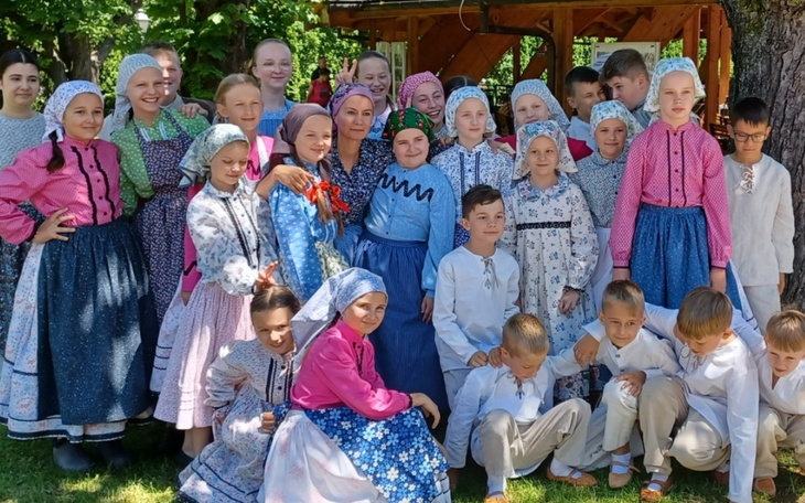 Grupa dzieci w tradycyjnych strojach ludowych, pozująca do zdjęcia.