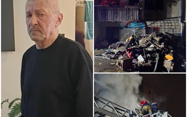 Mężczyzna w czarnym swetrze, stojący w pomieszczeniu.