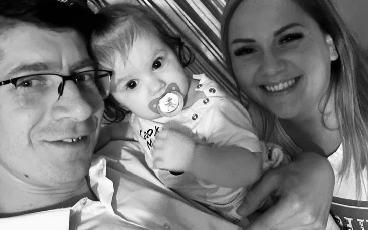 Rodzina pozująca do zdjęcia, uśmiechnięta z dzieckiem.