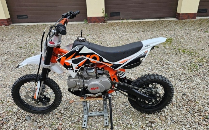 Motocykl dziecięcy na podjeździe, gotowy do jazdy.