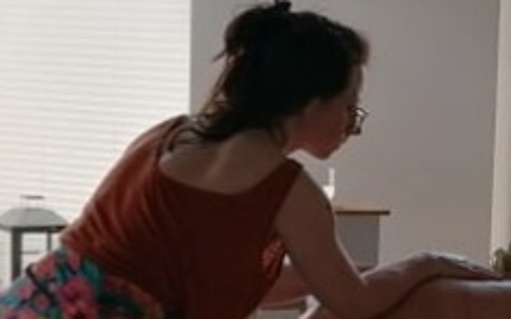 Kobieta w okularach, pochylona nad stołem w jasnym wnętrzu.