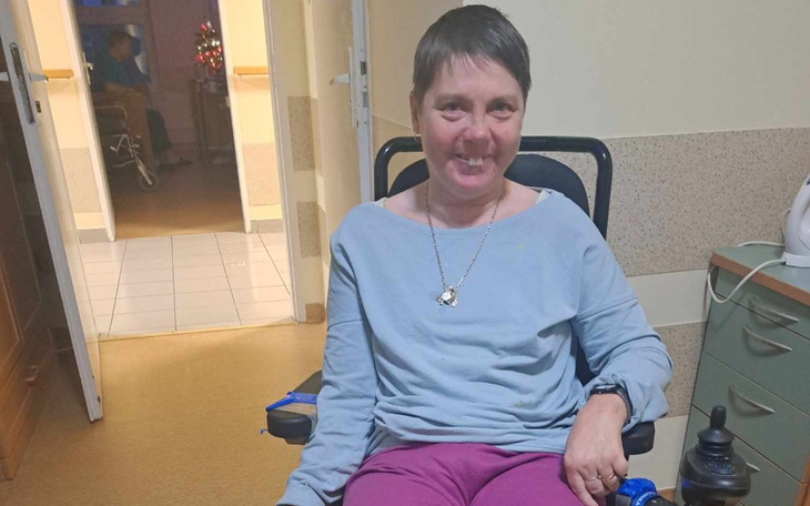 Kobieta na wózku inwalidzkim uśmiecha się do kamery.