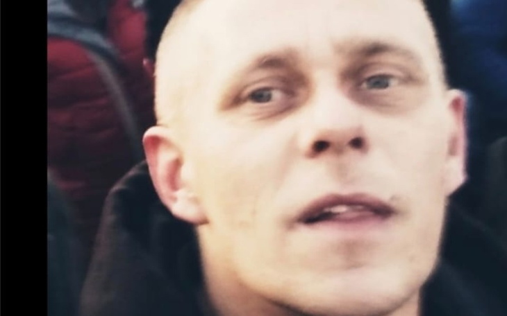 Portret mężczyzny w tłumie, z wyrazem skupienia na twarzy.