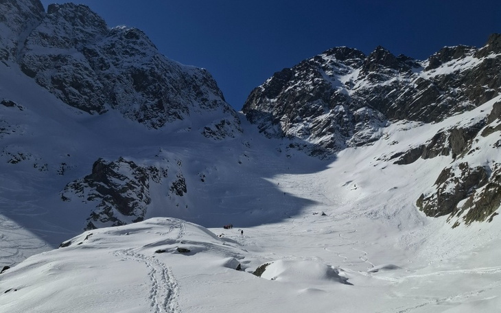 Górski krajobraz pokryty śniegiem, z wysokimi szczytami w tle.