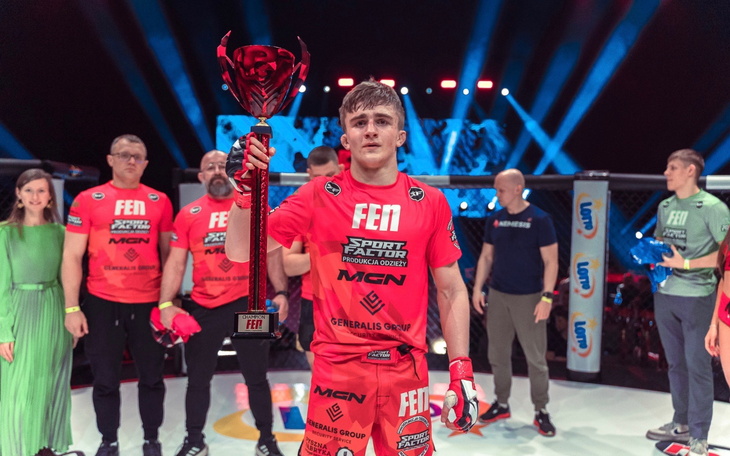 Młody zawodnik trzymający trofeum po wygranej walce.