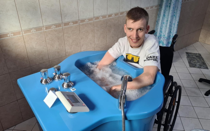 Mężczyzna w wózku inwalidzkim korzysta z kąpieli w wannie.