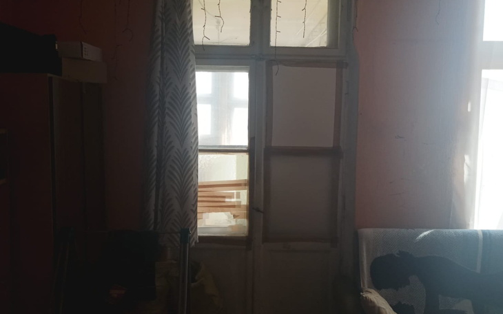 Pusty pokój z oknem i kanapą, w tle cień psa.