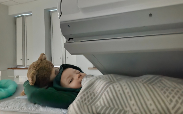 Dziecko leży w łóżku z pluszowym misiem.