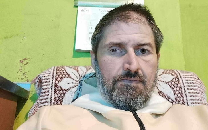 Mężczyzna z brodą siedzący na kanapie w zielonym pomieszczeniu.