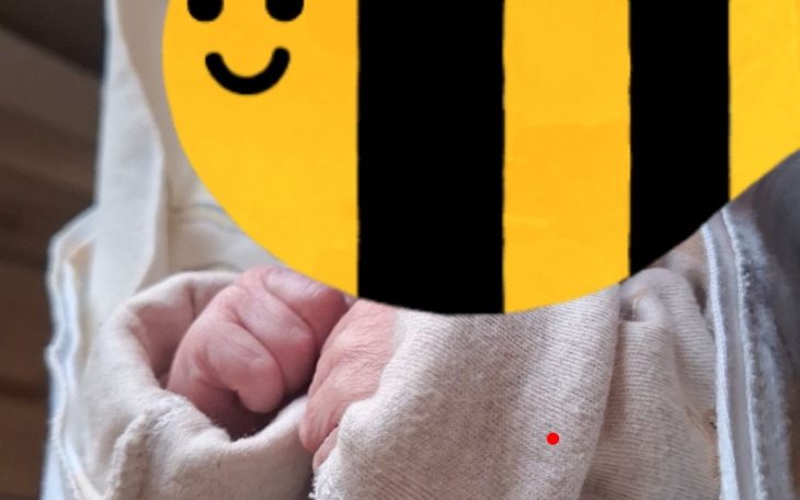 Dziecięce rączki w ubraniu, z rysunkiem pszczoły.