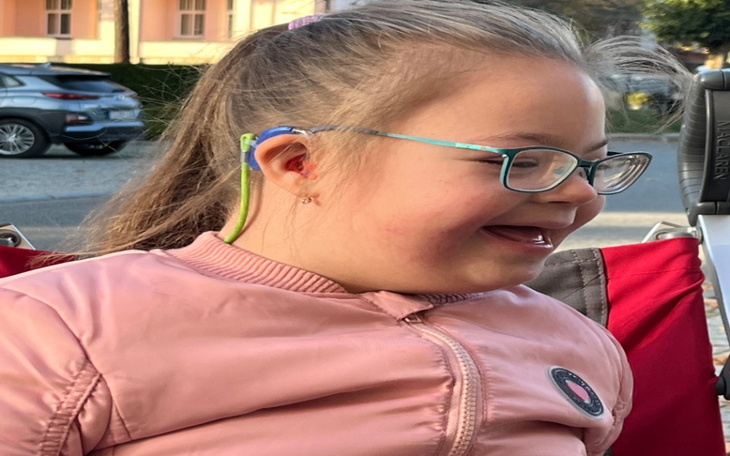 Uśmiechnięta dziewczynka w różowej kurtce.