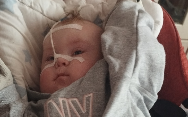 Małe dziecko z rurką tlenową, leżące w foteliku.