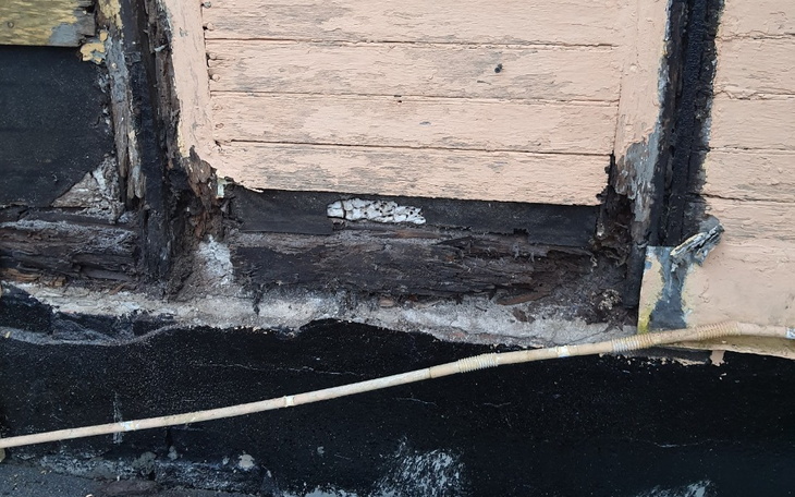 Zniszczona ściana budynku z widocznymi uszkodzeniami.