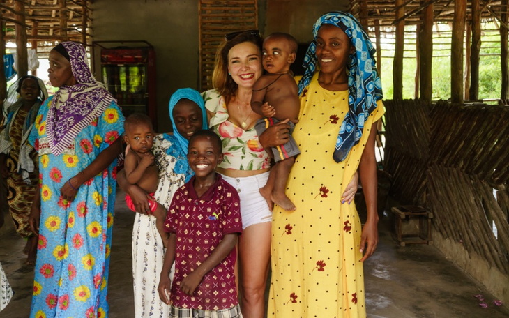 Grupa ludzi w tradycyjnych strojach w wiejskiej chacie.