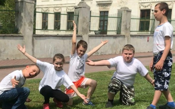 Grupa dzieci bawiących się na trawie, pozująca do zdjęcia.