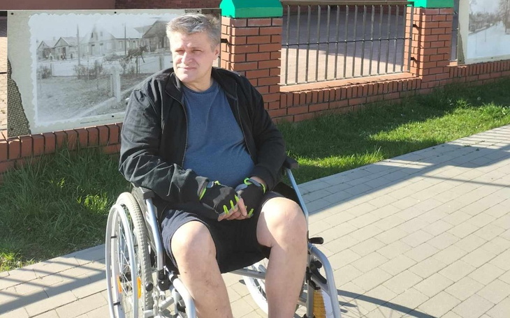 Mężczyzna na wózku inwalidzkim, siedzący na chodniku.