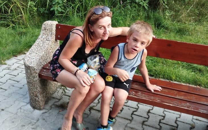 Kobieta i dziecko siedzą na ławce w parku.