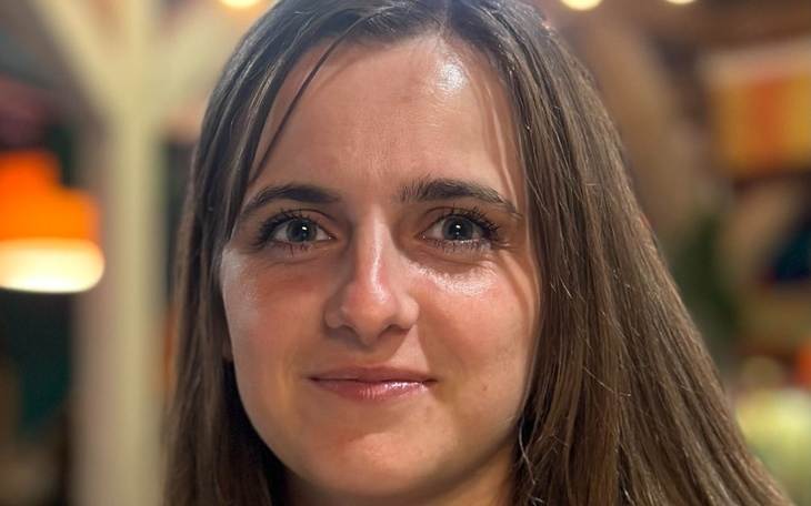 Portret młodej kobiety z uśmiechem, w ciepłym oświetleniu.