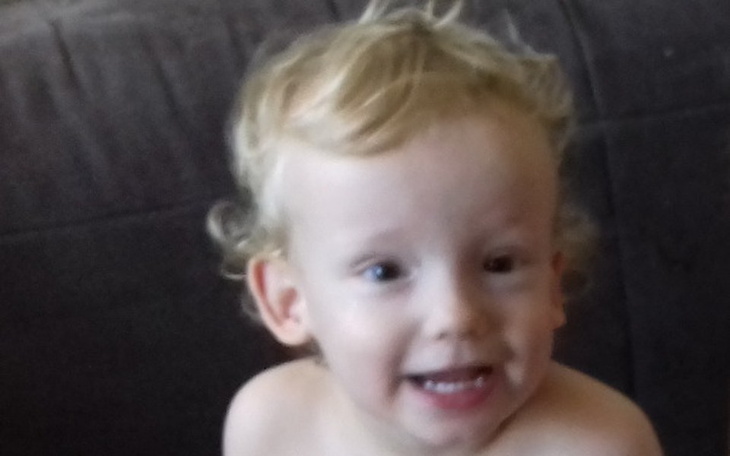 Mały chłopiec z uśmiechem, siedzący na kanapie.