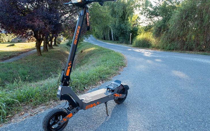 Elektryczna hulajnoga na drodze, w otoczeniu zieleni.