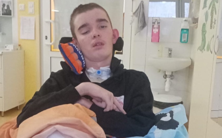 Chłopiec w wózku inwalidzkim, z wyrazem twarzy pełnym emocji.