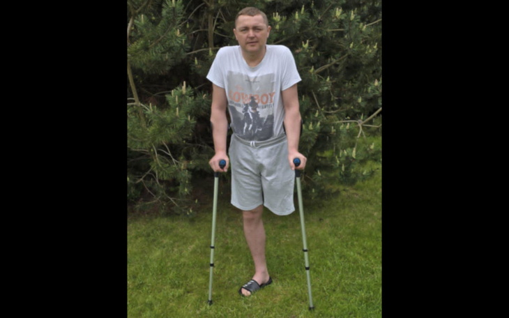 Mężczyzna na kulach w ogrodzie.