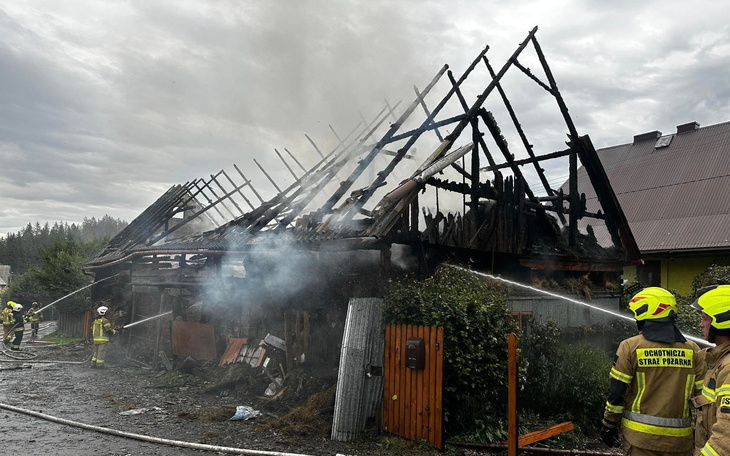 Zniszczony budynek po pożarze, strażacy gaszą ogień.