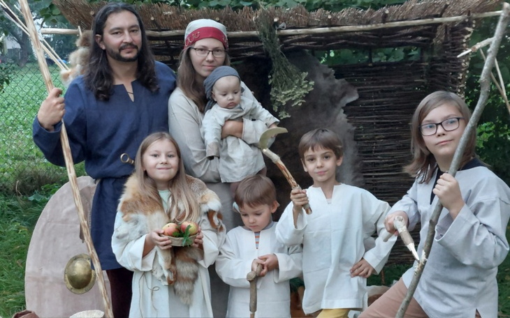 Rodzina w strojach historycznych, pozująca na tle naturalnym.