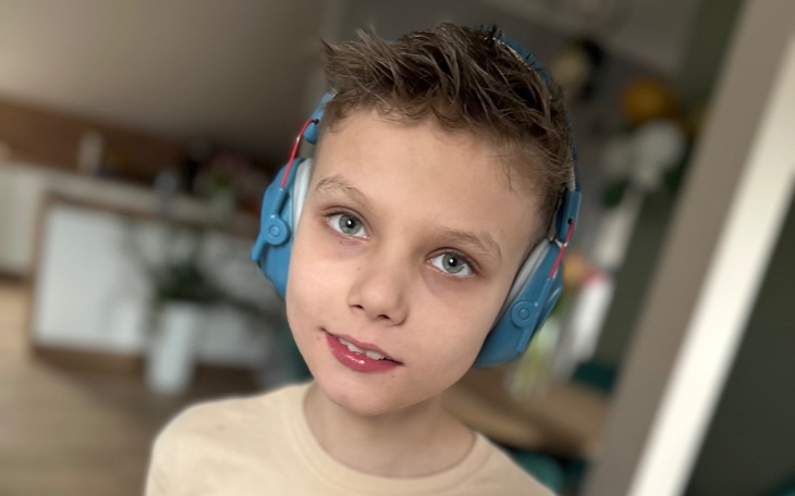 Chłopiec w słuchawkach, uśmiechający się do kamery.