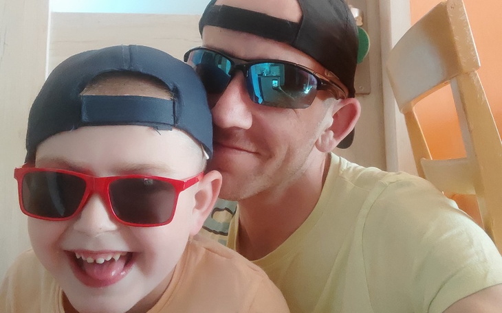 Mężczyzna i chłopiec w okularach przeciwsłonecznych, uśmiechają się do zdjęcia.