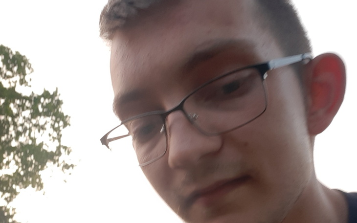 Młody mężczyzna w okularach, selfie w plenerze.