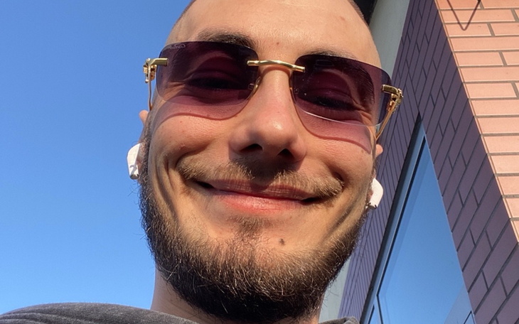 Mężczyzna w okularach przeciwsłonecznych, uśmiechający się do kamery.