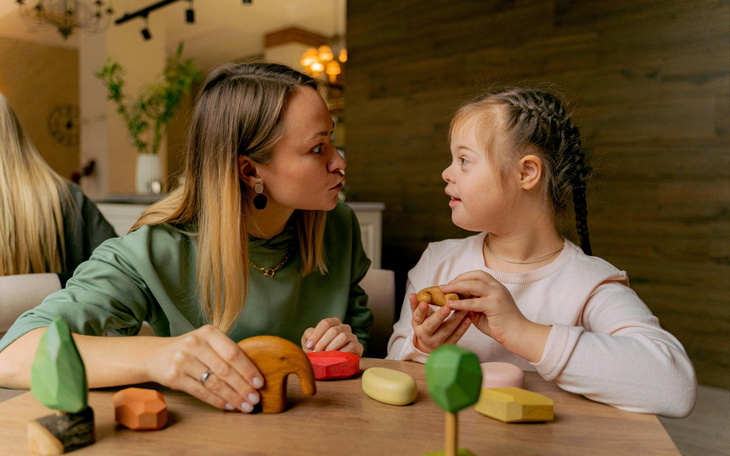 Kobieta i dziewczynka bawią się drewnianymi zabawkami.