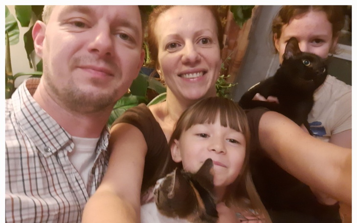 Rodzina pozująca do zdjęcia z kotami i zwierzętami domowymi.