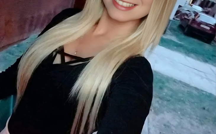 Kobieta z długimi włosami, uśmiechająca się do kamery.