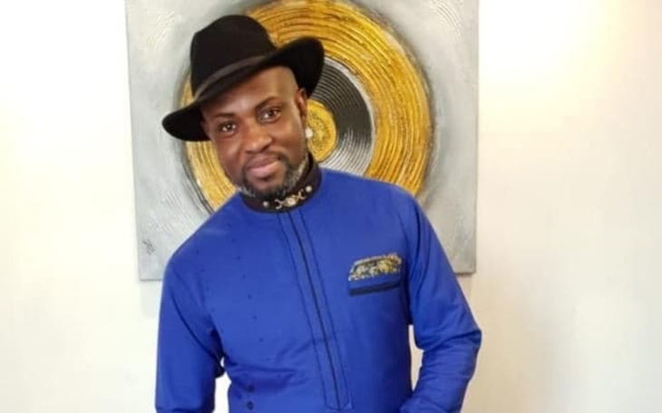 Mężczyzna w kapeluszu stoi przed abstrakcyjnym obrazem.