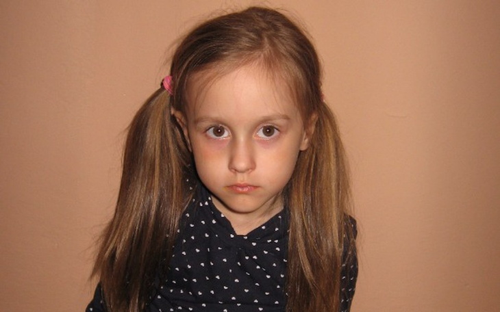 Dziewczynka z poważnym wyrazem twarzy, patrząca w obiektyw.