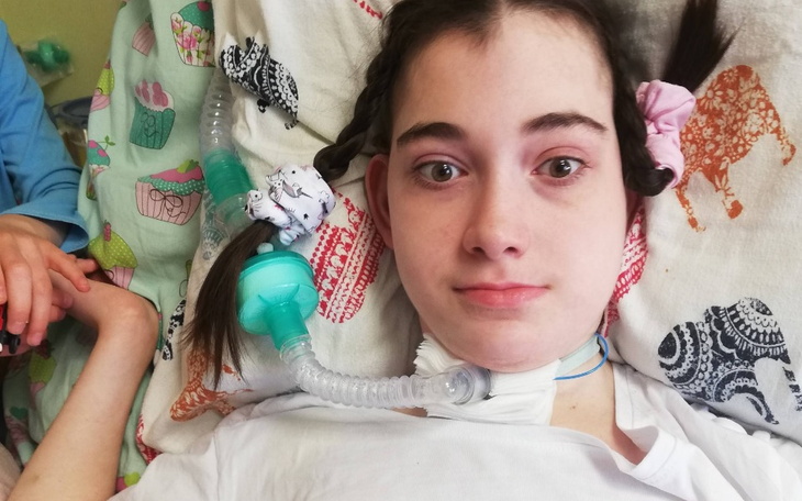 Dziewczyna z rurką tracheostomijną na poduszce.