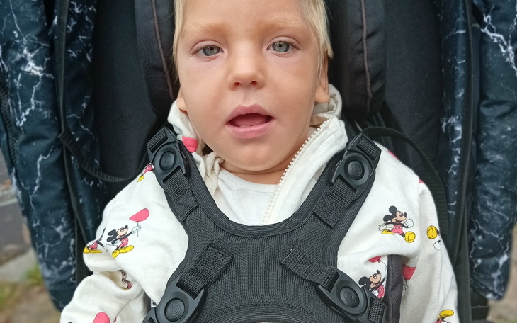 Dwie dziewczynki, uśmiechnięte, siedzące na kanapie.