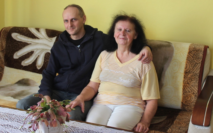 Mężczyzna i kobieta siedzący na kanapie, uśmiechnięci.