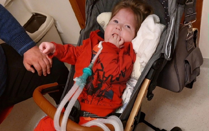 Małe dziecko w wózku, z rurką do oddychania.