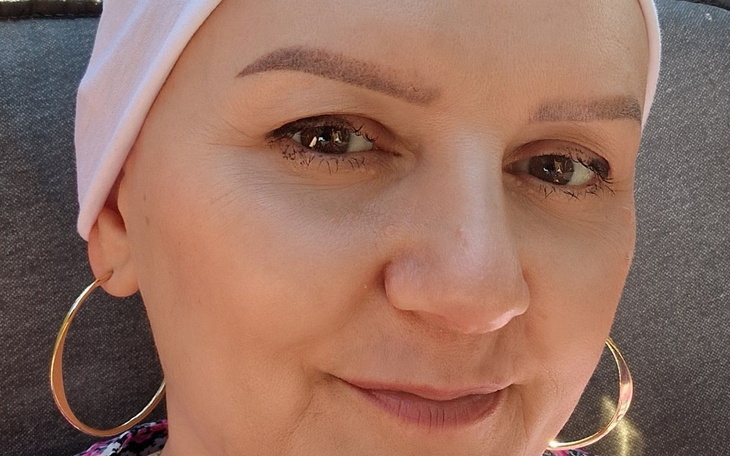 Kobieta w chustce, uśmiechająca się do kamery.